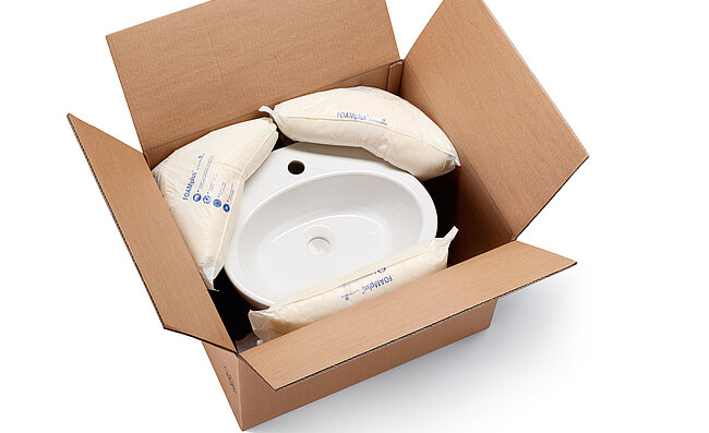 A cardboard box containing a washbasin and foam packaging