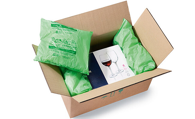 A box with a box of wine glasses padded with plastic bags with packing chips