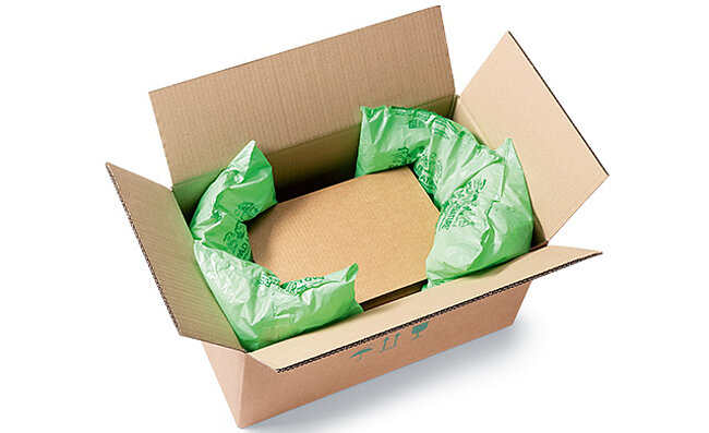 A box with a box inside padded with plastic bags with packing chips
